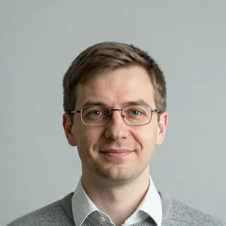 Портрет преподавателя физики: мужчина в очках и сером свитере
